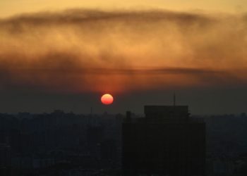 TOPSHOT - This general view taken on March 19, 2022 shows the sunset over Kyiv as smoke rises from the western outskirts of the city. (Photo by Aris Messinis / AFP) (Photo by ARIS MESSINIS/AFP via Getty Images)