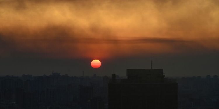 TOPSHOT - This general view taken on March 19, 2022 shows the sunset over Kyiv as smoke rises from the western outskirts of the city. (Photo by Aris Messinis / AFP) (Photo by ARIS MESSINIS/AFP via Getty Images)
