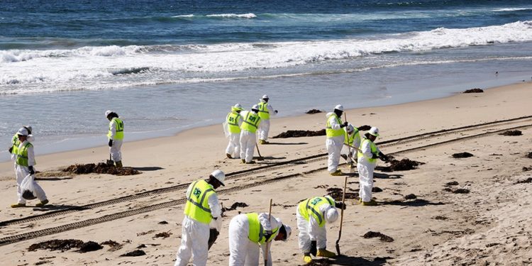 HUNTINGTON BEACH, CALIFORNIA - OCTOBER 09: Cleanup workers search for contaminated sand and seaweed along the mostly empty Huntington Beach about one week after an oil spill from an offshore oil platform on October 9, 2021 in Huntington Beach, California. The heavy crude oil spill affected close to 25 miles of coastline in Orange County. Huntington Beach is open but the public is not allowed to enter the water.  (Photo by Mario Tama/Getty Images)