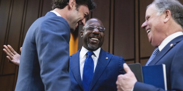UNITED STATES - MARCH 23: From left, Sens. Jon Ossoff, D-Ga., Raphael Warnock, D-Ga., and former Sen. Doug Jones, G-Ala., talk before Judge Ketanji Brown Jackson, President Biden’s nominee for Associate Justice to the Supreme Court, arrived on the third day of her Senate Judiciary Committee confirmation hearing in Hart Senate Office Building on Capitol Hill, on Wednesday, March 23, 2022. (Tom Williams/CQ Roll Call).