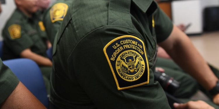 A US Customs and Border patrol agent looks on as US President Donald Trump speaks during  a roundtable on immigration and border security at the US Border Patrol Calexico Station in Calexico, California, April 5, 2019. - President Donald Trump landed in California to view newly built fencing on the Mexican border, even as he retreated from a threat to shut the frontier over what he says is an out-of-control influx of migrants and drugs. (Photo by SAUL LOEB / AFP)        (Photo credit should read SAUL LOEB/AFP via Getty Images)