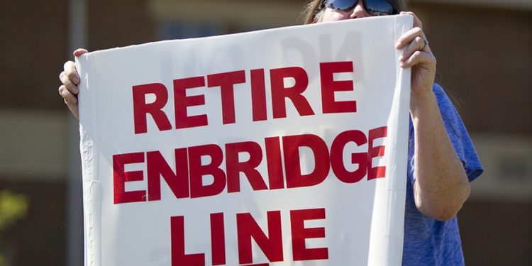 FILE - In this July 6, 2017, file photo, Lauren Sargent, takes part in a protest before the Enbridge Line 5 pipeline public information session in Holt, Mich. The U.S. and Canada will discuss the future of Enbridge Energy's Line 5, a key segment of a pipeline network that crosses part of the Great Lakes and is the subject of rising tension over whether it should be shut down, the White House said Monday, Nov. 8, 2021. (Cory Morse/The Grand Rapids Press via AP, File)