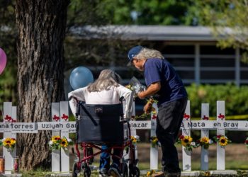UVALDE, TEXAS - MAY 26: A family places flowers down at a memorial following a mass shooting at Robb Elementary School on May 26, 2022 in Uvalde, Texas. According to reports, 19 students and 2 adults were killed, with the gunman fatally shot by law enforcement. (Photo by Brandon Bell/Getty Images)