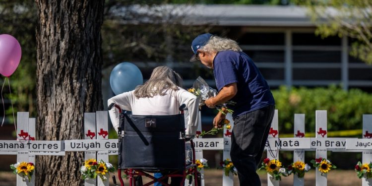 UVALDE, TEXAS - MAY 26: A family places flowers down at a memorial following a mass shooting at Robb Elementary School on May 26, 2022 in Uvalde, Texas. According to reports, 19 students and 2 adults were killed, with the gunman fatally shot by law enforcement. (Photo by Brandon Bell/Getty Images)