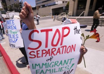 A demonstrator holding a flower and a sign protests outside Long Beach Convention Center to urge the release of immigrant children from ICE detention centers outside Long Beach Convention Center in Long Beach, California, on May 8, 2021. (Photo by RINGO CHIU / AFP) (Photo by RINGO CHIU/AFP via Getty Images)
