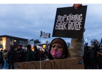 A demonstrator holds a sign reading "Stop Killing Black People" as she stands outside the Brooklyn Center police station while protesting the death of Daunte Wright who was shot and killed by a police officer in Brooklyn Center, Minnesota on April 14, 2021.