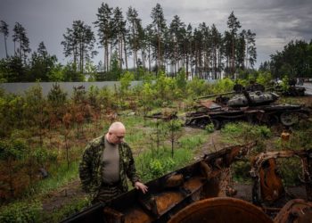 A local resident examines a destroyed Russian tank outside Kyiv on May 31, 2022, amid the Russian invasion of Ukraine. (Photo by Dimitar DILKOFF / AFP) (Photo by DIMITAR DILKOFF/AFP via Getty Images)