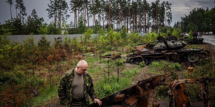 A local resident examines a destroyed Russian tank outside Kyiv on May 31, 2022, amid the Russian invasion of Ukraine. (Photo by Dimitar DILKOFF / AFP) (Photo by DIMITAR DILKOFF/AFP via Getty Images)
