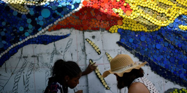 Venezuelan mural artist uses recycled plastic to light up Caracas suburb